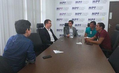 Na foto, estão os procuradores da República, os indígenas e o senador, ao redor de uma mesa em uma sala que possui uma das paredes adesivada com a marca do MPF