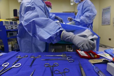 Imagem mostra uma sala de cirurgia, e, em primeiro plano, uma bandeja com instrumentos cirúrgicos 
