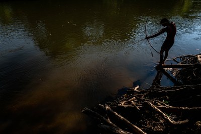 Foto mostra um indígena arremessando uma flecha em um rio