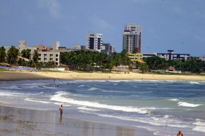 Imagem da Praia do Bessa no Paraíba mostrando o mar e a faixa de areia com prédios ao fundo.