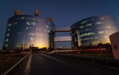 Foto noturna dos prédios que abrigam a procuradoria-geral da república, em brasília. A foto mostra dois prédios redondos, interligados e revestidos de vidro.