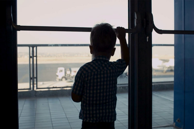 #pracegover: foto de uma criança pequena de costas olhando através de uma porta de vidro. A foto é de reprodução do Interesse Público.