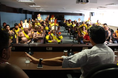 Foto do procurador à mesa com indígenas no auditório.