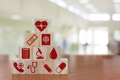 #ParaTodosVerem: fotografia de vários blocos de madeira de brinquedo, com gravuras com temas médicos pintadas neles na cor vermelha: uma injeção, um coração, um estetoscópio, um comprimido, um curativo, uma radiografia.