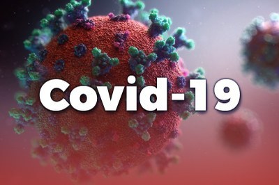 A palavra Covid-19 sobre a ilustração de um coronavírus: uma esfera vermelha com espículas sobre sua superfície, semelhantes a uma coroa.