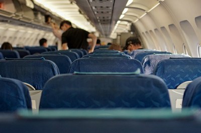 #Paratodosverem: Imagem mostra interior de uma cabine de avião comercial vista do fundo para a frente, com assentos azuis vagos e passageiros se levantando