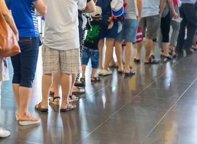 Fila de pessoas. Imagem mostra as pernas de diversas pessoas que esperam em uma fila