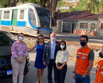 Foto de 6 pessoas de pé uma ao lado da outra, em uma rua. Todas usam máscaras faciais que cobrem o nariz e a boca.