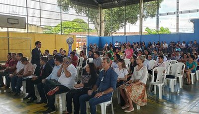 Imagem mostra assembleia sentada em cadeiras em quadra de escola no bairro Colônia Antônio Aleixo