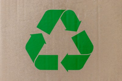 Símbolo de reciclagem na cor verde em sobreposição a um papelão
