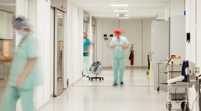 #ParaTodosVerem. Fotografia de corredor de hospital no qual se encontram três médicos. As imagens dos três médicos estão embaçadas e tremidas. A foto é da Stockphotos.