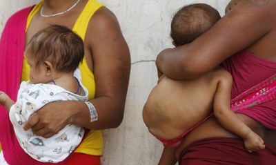 Foto de dois bebês indígenas no colo de suas mães
