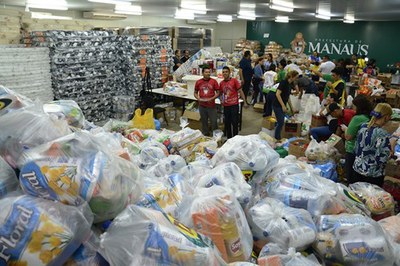 Galpão da Prefeitura de Manaus tomado por fardos de alimentos e materiais de higiene e limpeza, colchões e outros donativos destinados às famílias vítimas do incêndio no bairro Educandos