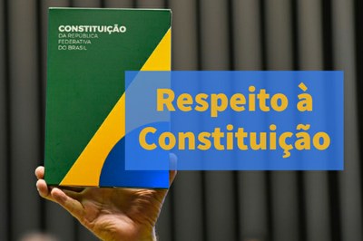 Uma mão ergue livro verde, amarelo e azul intitulado Constituição da República Federativa do Brasil. Na arte, há um letreiro azul sobreposto à imagem do livro, escrito "Respeito à Constituição"