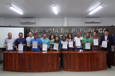 Foto mostra os 12 integrantes dos órgãos públicos e das comunidades segurando cópia do acordo após assinatura