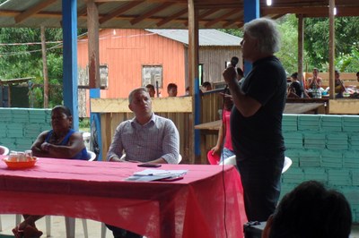 Foto durante reunião na terra indígena Uaçá, homem, de pé, fala ao microfone. 