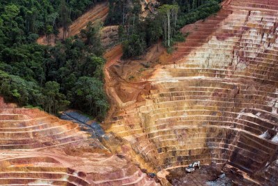 Foto aérea mostra um poço de escavação para extração de minério onde há água ao centro e algumas árvores no entorno