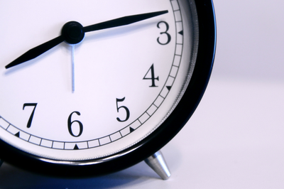 Fotografia exibe o recorte de um relógio de ponteiro preto, marcando 8h10