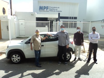 Na fotografia, o representante da Rodaleve entrega as chaves de um veículo ao representante da Cotefave, em frente a um carro pequeno branco. Ao lado, estão representantes do MPF. Todos usam máscara.