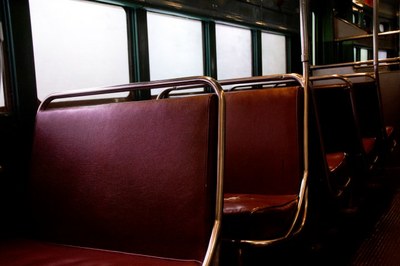 A imagem mostra o interior de um ônibus escolar, com poltronas vermelhas vazias. 