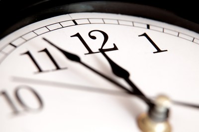 A fotografia apresenta o recorte de parte de um relógio que marca 11 horas e 55 minutos.
