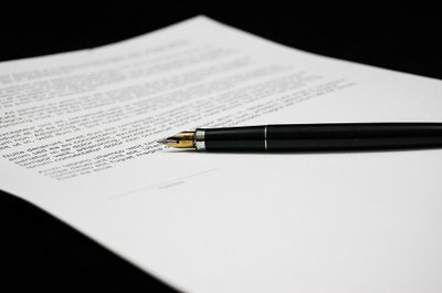 Foto mostra a imagem de uma caneta sobre uma folha de papel.