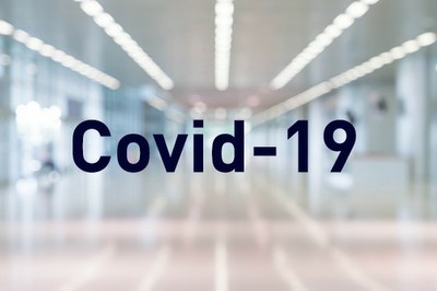 Fotografia mostra um corredor de hospital de forma desfocada e a palavra Covid-19
