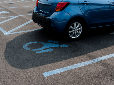 Fotografia ilustrativa mostra parte de um estacionamento com a marcação no chão para carros para pessoas com deficiência e um carro estacionado na vaga