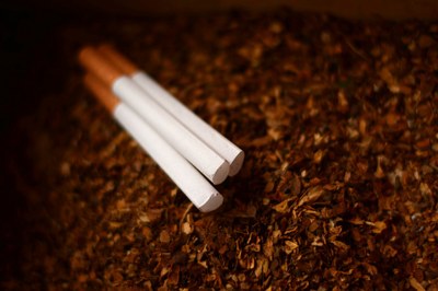 #pracegover Imagem mostra quatro cigarros sobre um fundo que parece fumo picado