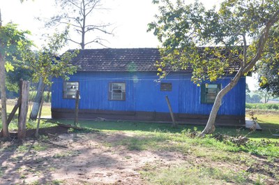 Foto de uma casa de madeira, em área rural, pintada na cor azul