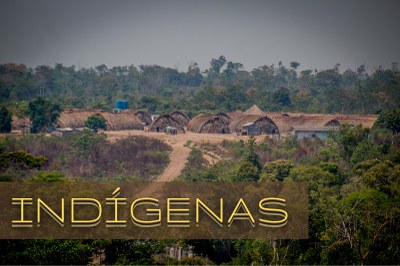Imagem de uma aldeia indígena em meio a uma floresta com a palavra "INDÍGENAS" escrita no canto inferior esquerdo e com a cor amarela.