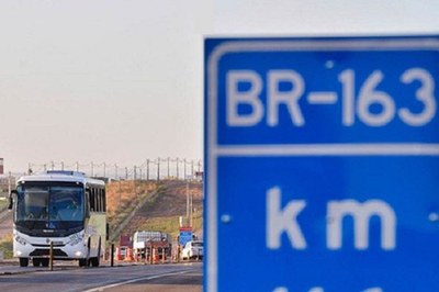 #Paratodosverem: Imagem mostra placa em primeiro plano identificando rodovia BR-163. Ao fundo, ônibus trafega na rodovia