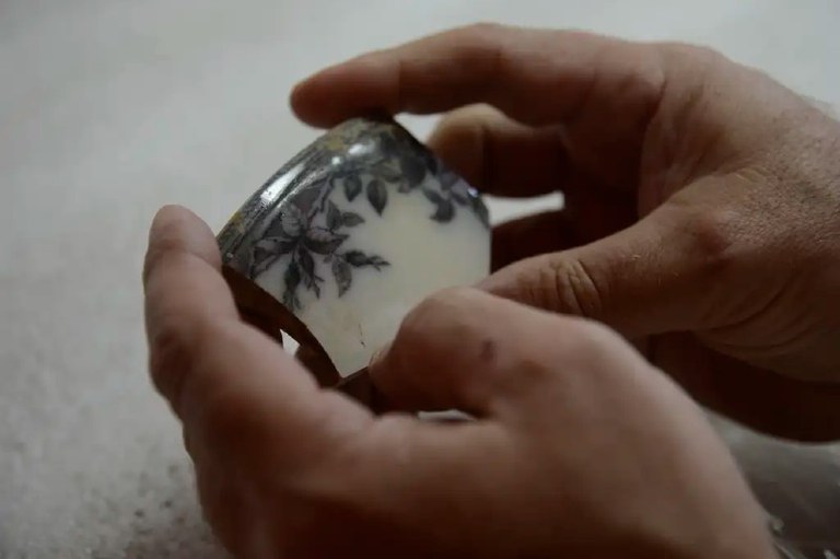 foto mostra detalhe de um fragmento de cerâmica nas mãos de uma pessoa