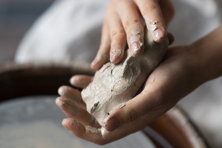 Imagem de uma mão feminina trabalhando a argila em um estúdio
