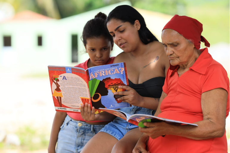 Três mulheres da comunidade lendo.