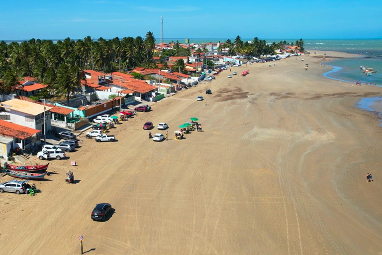 Foto aérea da Praia do Peba onde vê-se banhistas, carros, motos e ônibus na faixa de areia