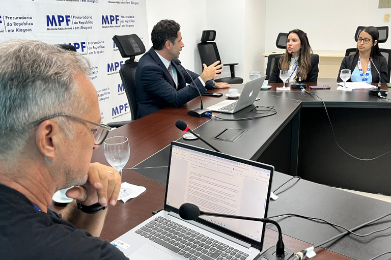 Registro fotográfico das pessoas reunidas em torno da mesa, com o procurador da República no centro da imagem