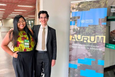 Foto mostra o procurador André Porreca e uma mulher ao lado do cartaz do evento