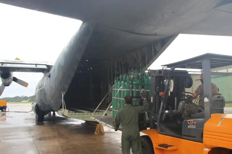 foto mostra cilindros de oxigênio sendo colocados em avião de carga