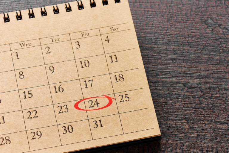 Foto de um calendário de mesa, sobre fundo escuro, com o dia 24 marcado com um círculo vermelho