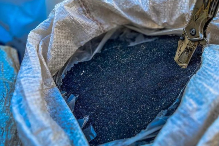 Foto mostra cassiterita em pó, armazena em um saco grande branco