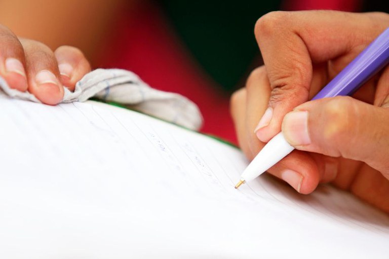 Foto em detalhe de uma pessoa escrevendo em um caderno