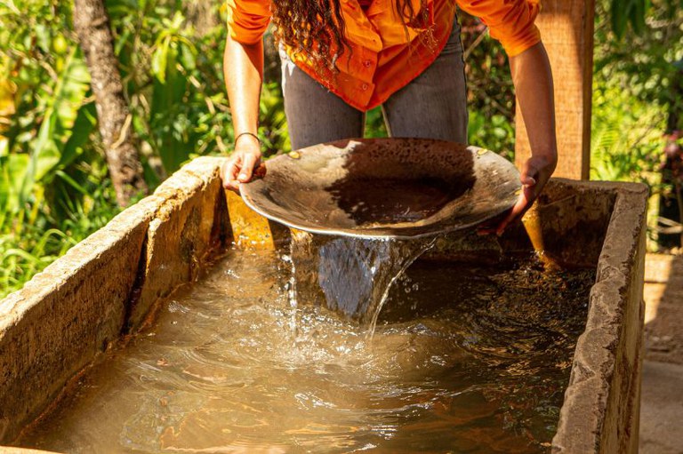 Foto em detalhe de uma pessoa garimpando ouro com uma bateia