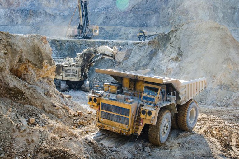 Foto mostra uma retroescavadeira em uma área de mineração