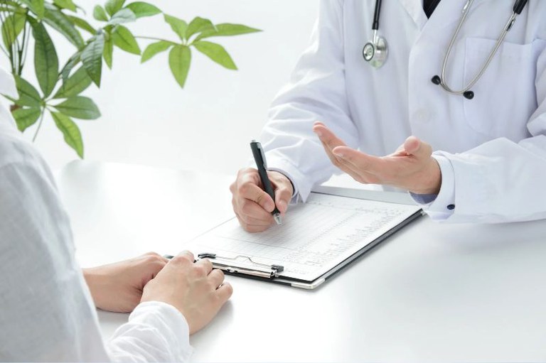 Imagem mostra um médico fazendo avaliação de paciente.