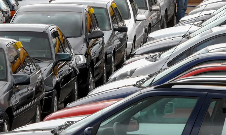 Fotografia em ângulo elevado mostrando diversos carros de diferentes modelos e cores estacionais lado a lado.
Os veículos aparecem alinhados e estacionados bem próximos uns dos outros, preenchendo todo o quadro.