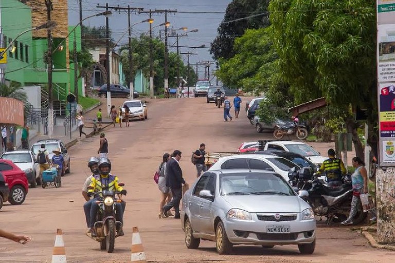 Foto mostra uma rua de Oiapoque, com pessoas, carros e motos