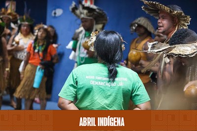 Uma imagem de um grupo de pessoas de uma tribo indígena, reunidas em uma sala.