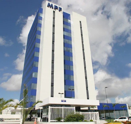 Fachada principal do edifício-sede do Ministério Público Federal (MPF), destacando a arquitetura moderna em tons de azul e branco sob um céu parcialmente nublado.