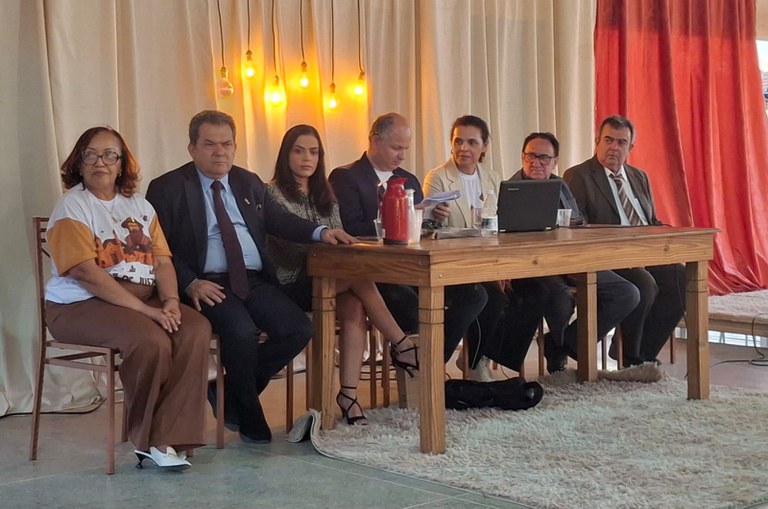 Imagem 1 - Um grupo de seis pessoas sorridentes, três homens e três mulheres, posa perto de um grande corpo d'água sob um céu nublado.